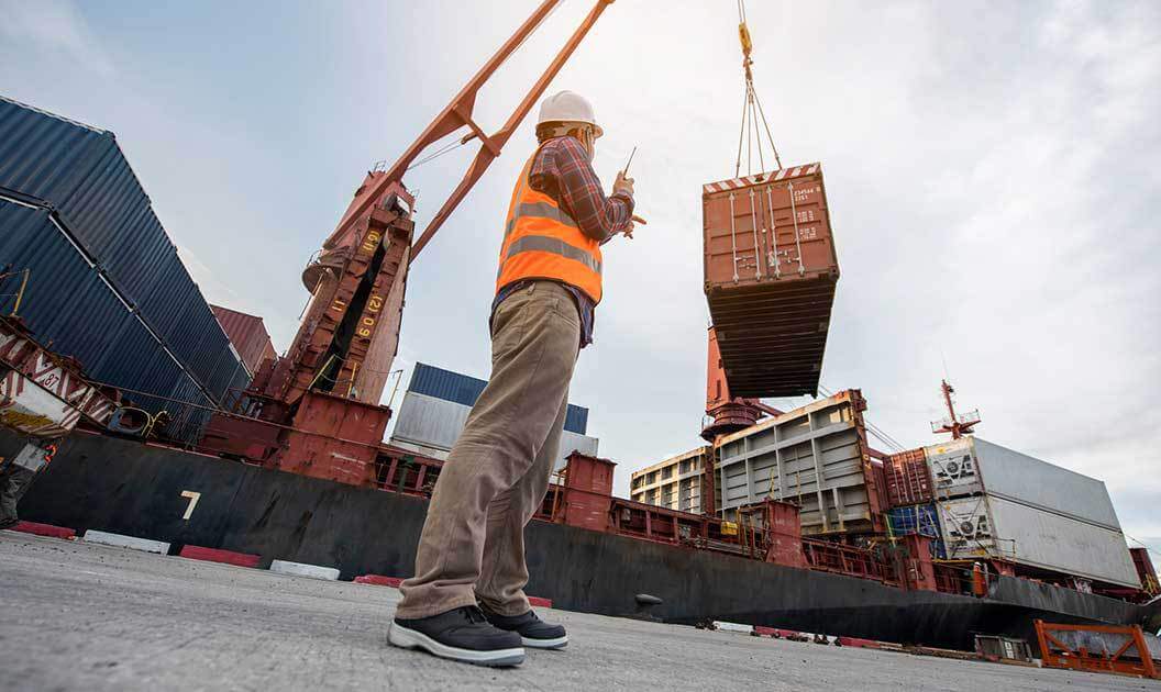A port worker overseeing the lifting of a cargo container